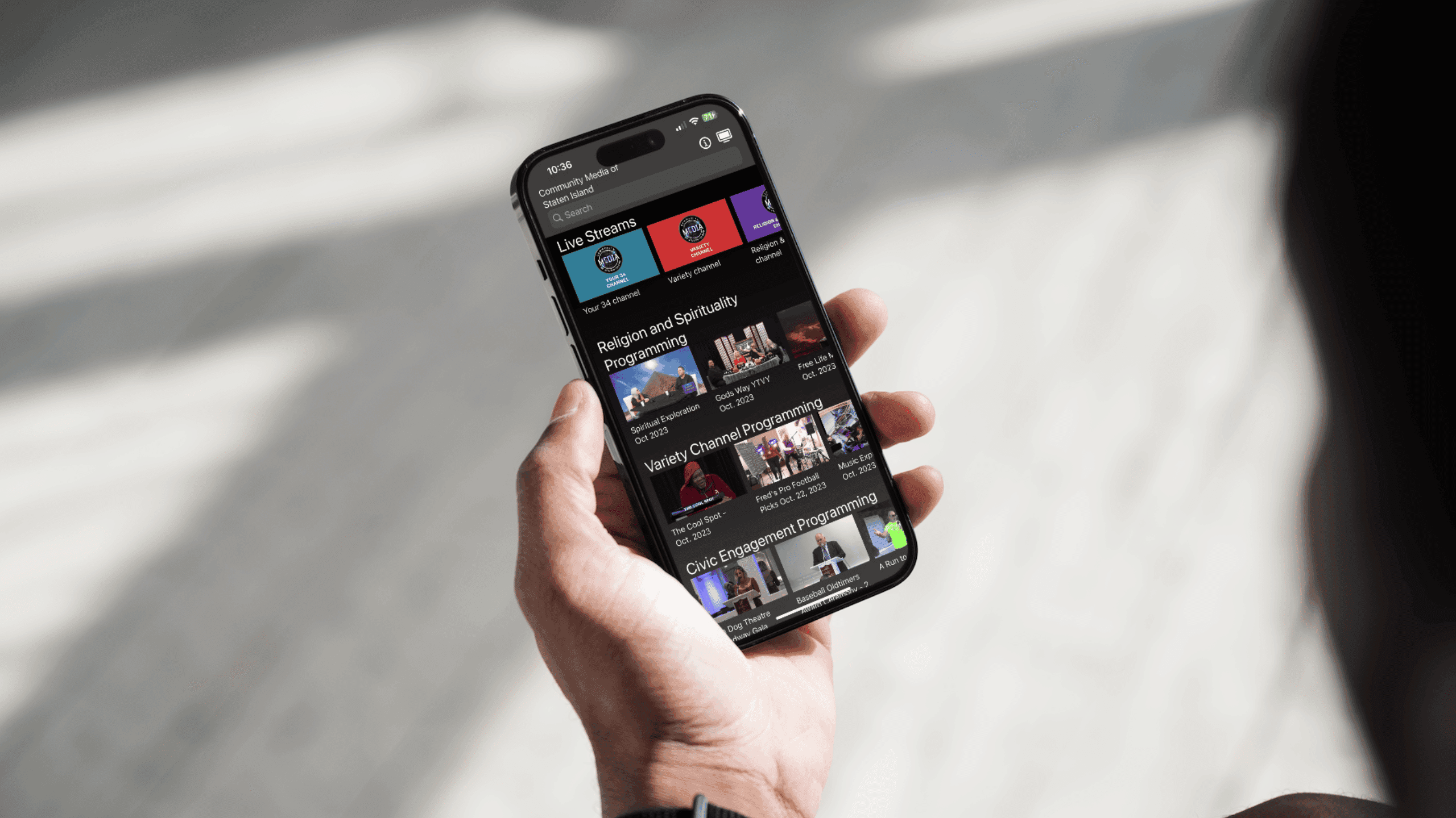 A hand holding a smartphone with Community Media of Staten Island's Mobile app