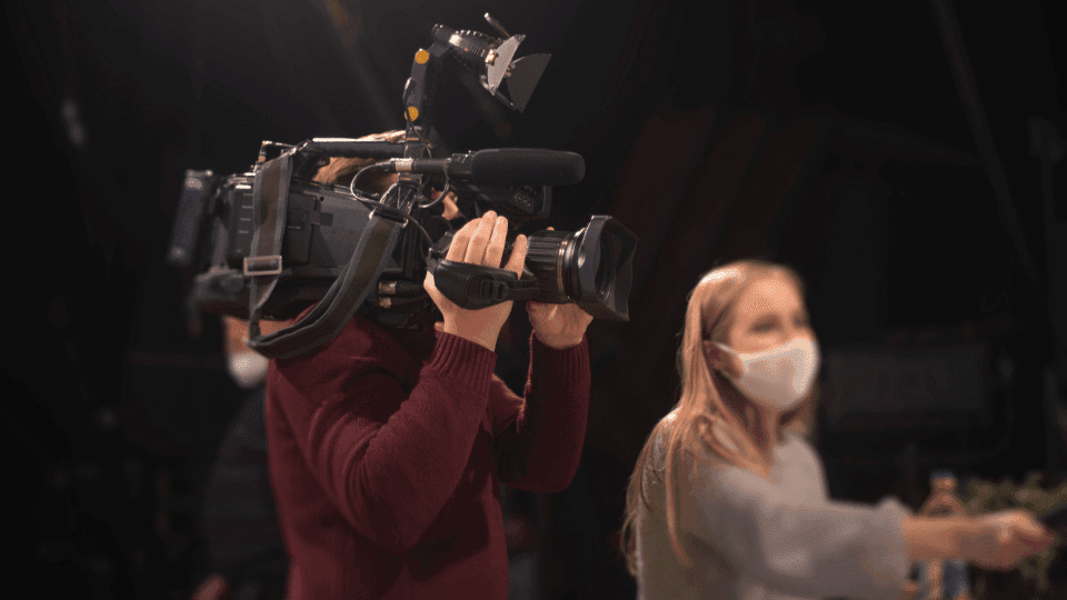 A man holds video production camera equipment while on set