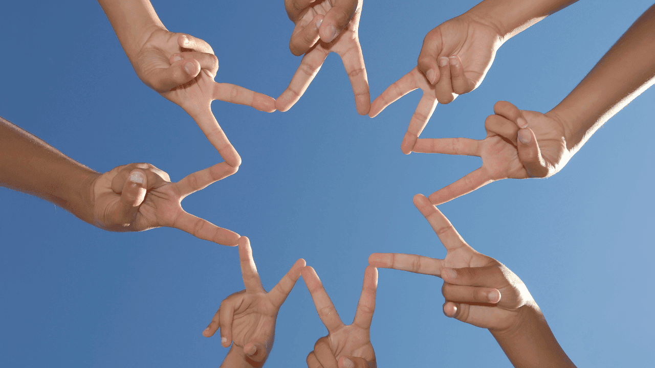 Human fingers come together to illustrate the shape of a star