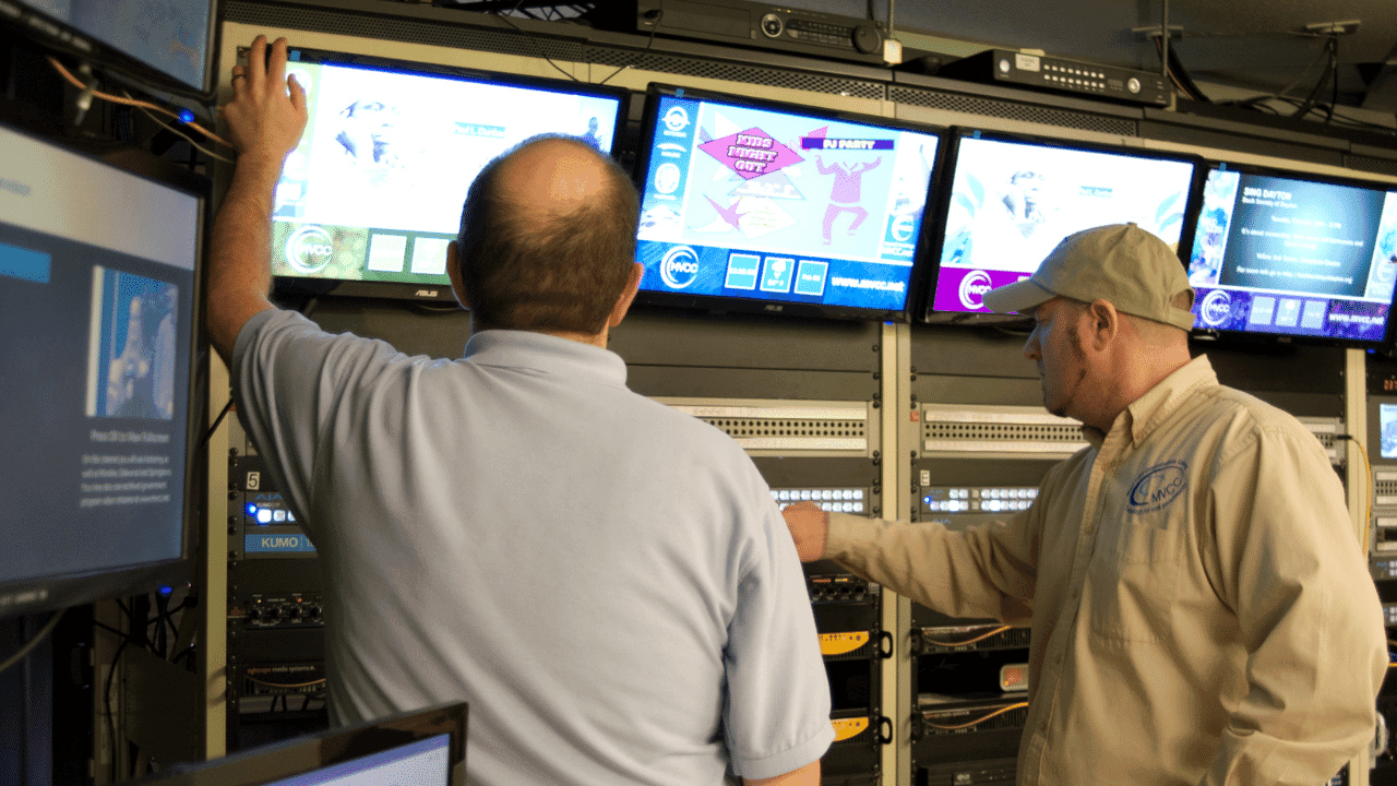 Two people take a look at video screens during video production for TV