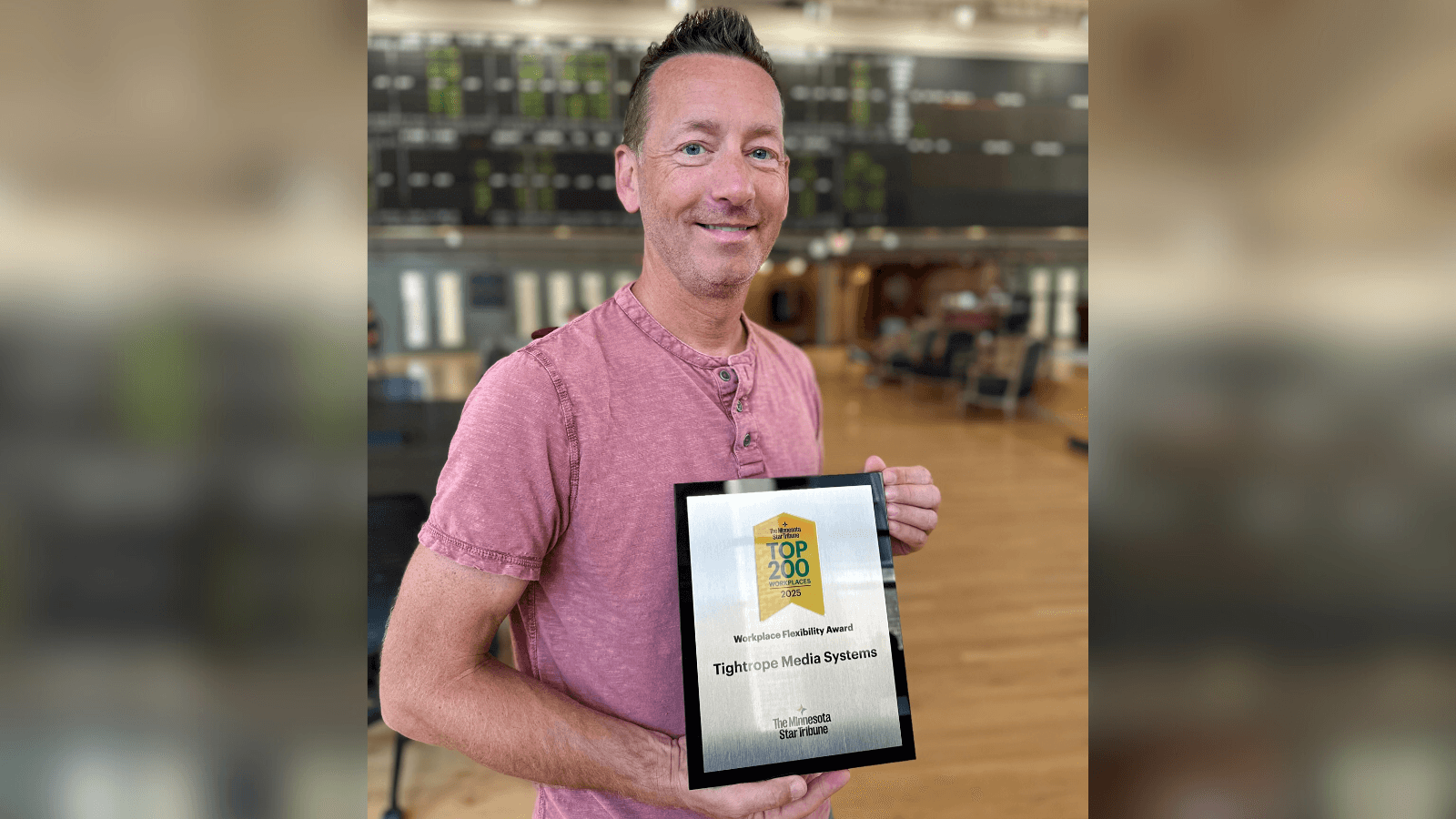 JJ Parker, CEO and co-founder of Tightrope Media Systems, stands indoors holding a framed award recognizing Tightrope as a 2025 Top 200 Workplace for Workplace Flexibility, presented by the Minnesota Star Tribune.